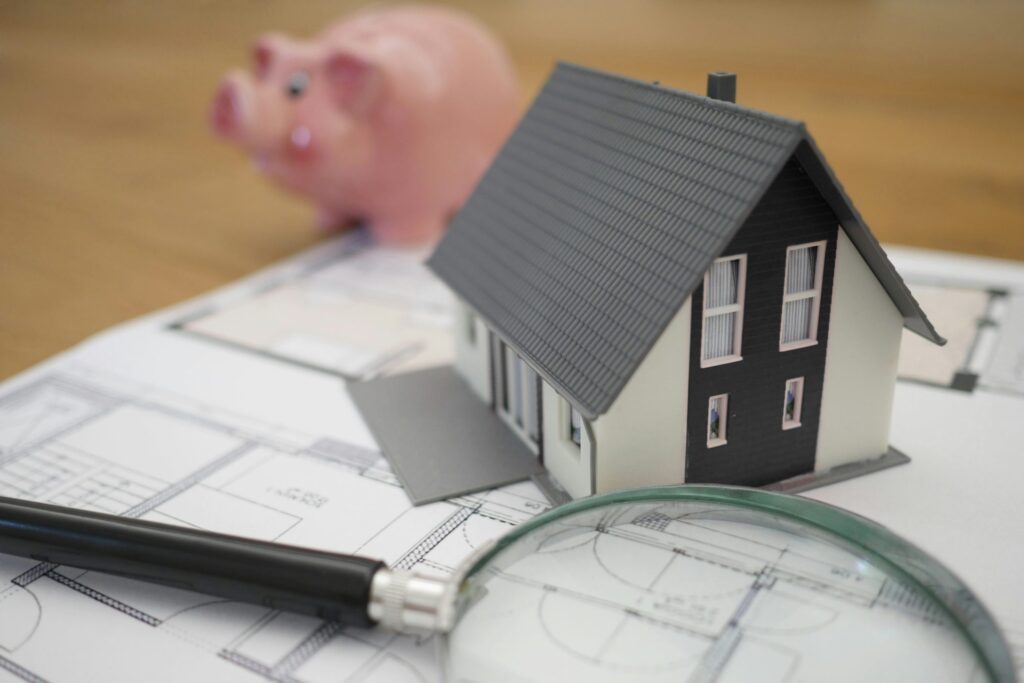 House model, floorplan piggy bank and magnifying glass